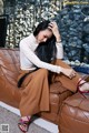 A woman sitting on a brown couch with her head in her hands.