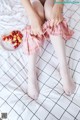 A woman sitting on a bed with a plate of cherries.