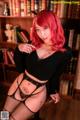 A woman with red hair wearing a black top and fishnet stockings.