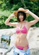 A woman in a pink bikini and a straw hat posing for a picture.