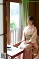 A woman in a pink kimono sitting at a table.