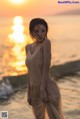 A woman standing on the beach at sunset. 