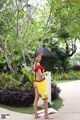 A woman in a red and white bathing suit holding a yellow bag.