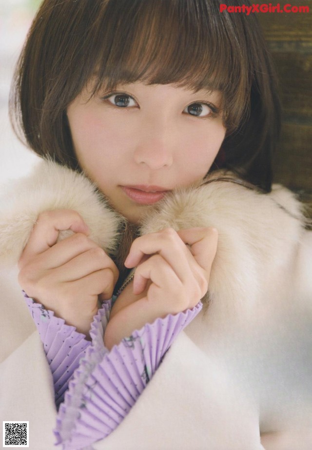 A woman in a white fur coat holding a purple fan.