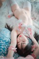 A woman laying on top of a bed with a teddy bear.