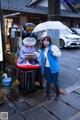 A woman holding an umbrella standing next to a statue.