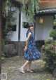 A woman in a blue dress is walking in a courtyard.