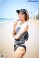 A woman in a bathing suit eating an ice cream cone on the beach.