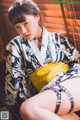 A woman in a blue and white kimono sitting on a chair.