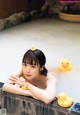 A woman laying in a bathtub with rubber ducks.