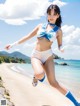 A woman in a blue and white bikini running on a beach.